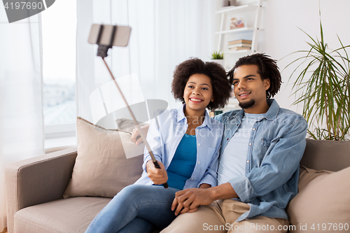 Image of happy couple with smartphone taking selfie at home