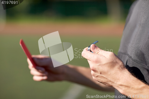 Image of referee hands with red card on football field