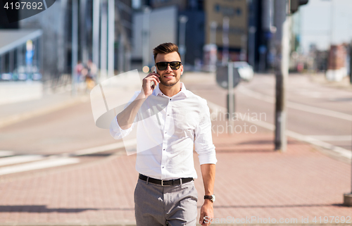 Image of happy man with smartphone calling on city street