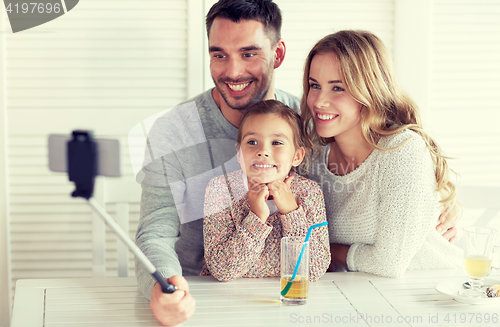Image of happy family taking selfie at restaurant
