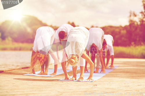Image of group of people making yoga exercises outdoors