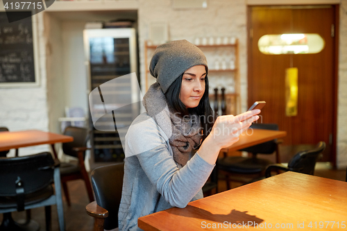 Image of young woman with smartphone at cafe