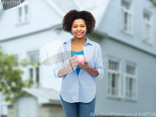 Image of happy afro american young woman with piggy bank