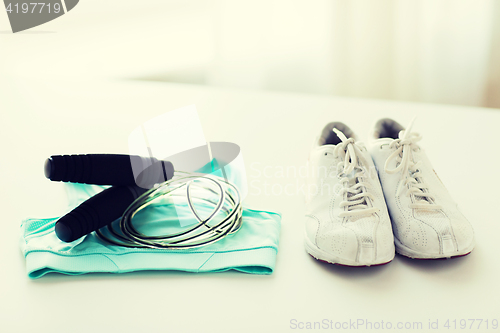 Image of close up of sports top, sneakers and skipping rope