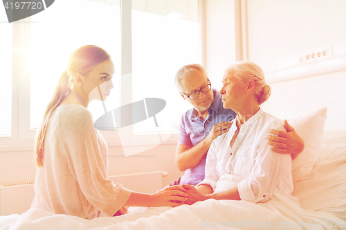 Image of family visiting ill senior woman at hospital