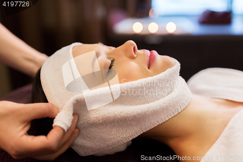 Image of woman having face massage with towel at spa