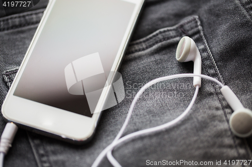 Image of smartphone and earphones on denim or jeans pocket