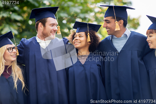 Image of happy students or bachelors in mortar boards