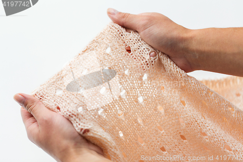 Image of close up of hands with knitted clothing item