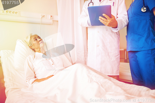 Image of doctor and nurse visiting senior woman at hospital