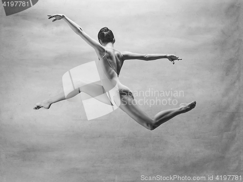 Image of Young beautiful modern style dancer jumping on a studio background