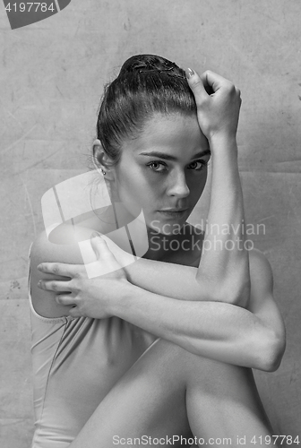 Image of Tired ballet dancer sitting on the wooden floor on a pink background