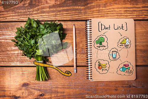Image of Blank notebook and pencil with a bunch of herbs on wooden table