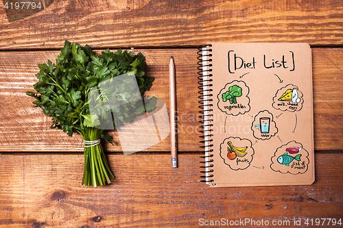 Image of Blank notebook and pencil with a bunch of herbs on wooden table