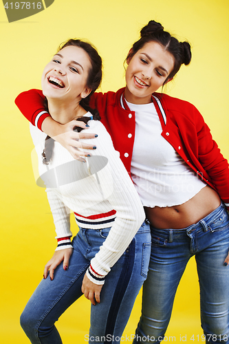 Image of lifestyle people concept: two pretty young school teenage girls having fun happy smiling on yellow background