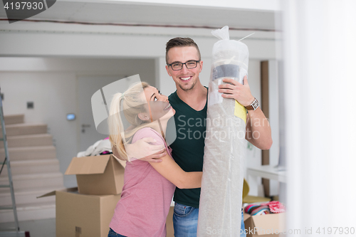 Image of couple carrying a carpet moving in to new home