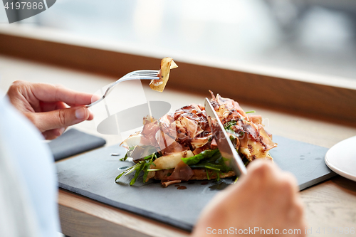 Image of woman eating prosciutto ham salad at restaurant