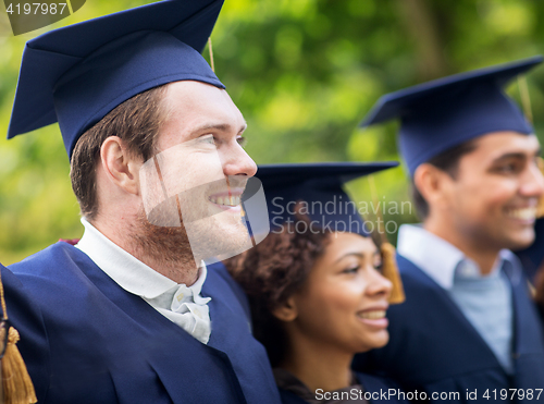 Image of happy students or bachelors in mortar boards