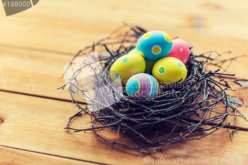 Image of close up of colored easter eggs in nest on wood