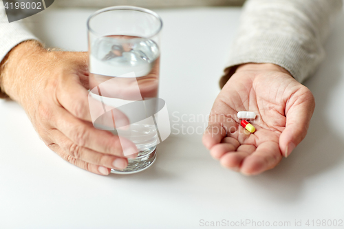 Image of close up of hands with medicine pills and water