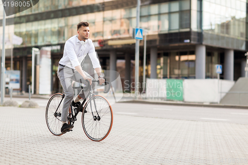 Image of man with headphones riding bicycle on city street