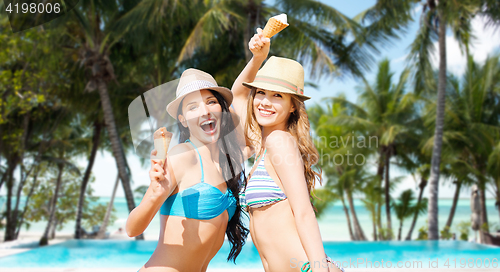 Image of smiling women eating ice cream on beach