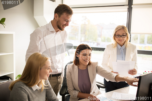 Image of happy creative team with computer in office