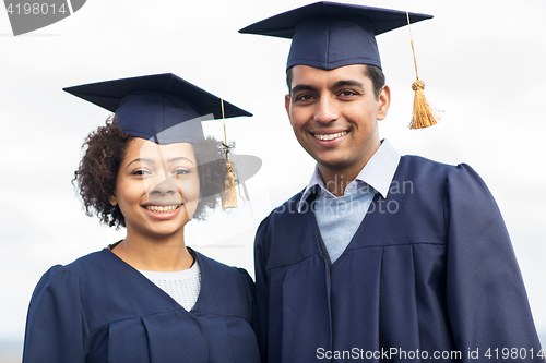 Image of happy students or bachelors in mortar boards