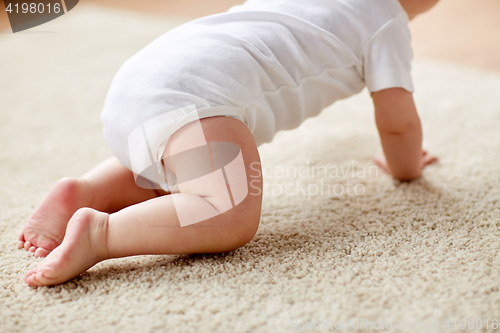 Image of little baby in diaper crawling on floor at home