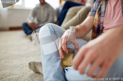 Image of close up of man with beer bottle and friends