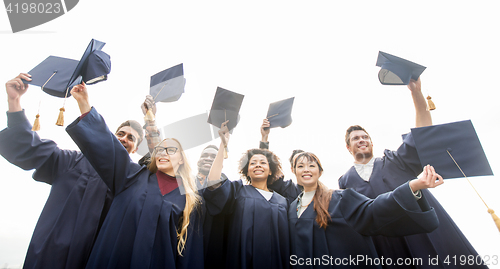 Image of happy students or bachelors waving mortar boards