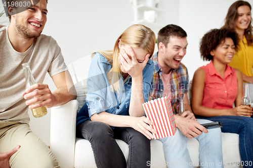 Image of happy friends with popcorn and beer at home