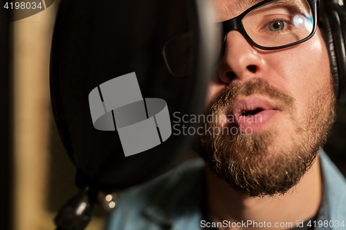 Image of man with headphones singing at recording studio