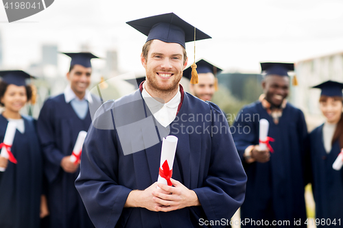 Image of happy students in mortar boards with diplomas