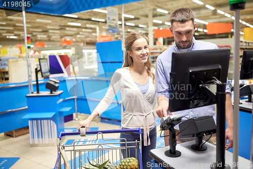 Image of couple buying food at grocery store cash register