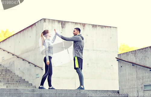 Image of happy couple giving high five outdoors