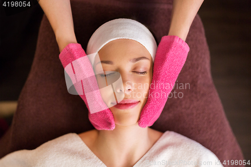 Image of woman having face massage with terry gloves at spa