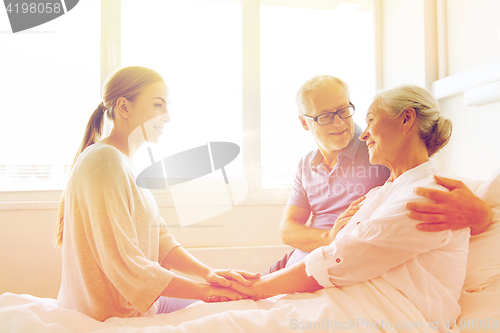 Image of happy family visiting senior woman at hospital