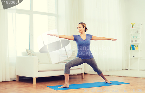 Image of woman making yoga warrior pose on mat