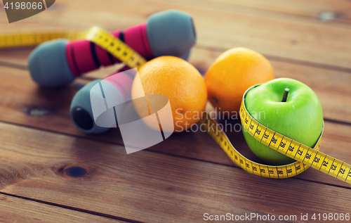 Image of close up of dumbbell, fruits and measuring tape