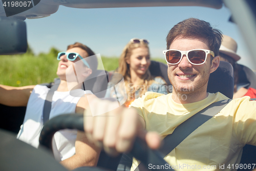 Image of happy friends driving in cabriolet car