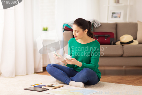 Image of happy woman with money and travel map at home