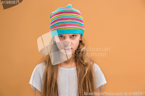Image of Angry young girl in hat looking at camera with hate
