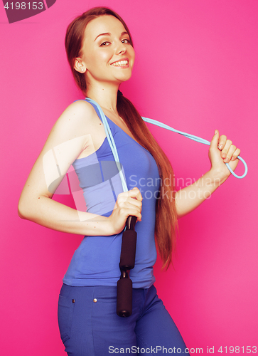 Image of young happy slim girl with skipping rope on pink background smil