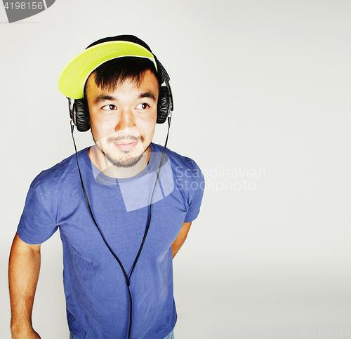 Image of young asian man in hat and headphones listening music on white b