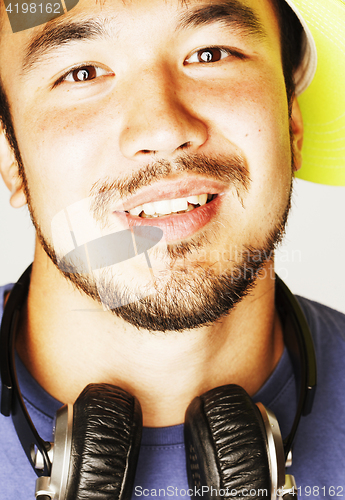 Image of young asian man in hat and headphones listening music on white b