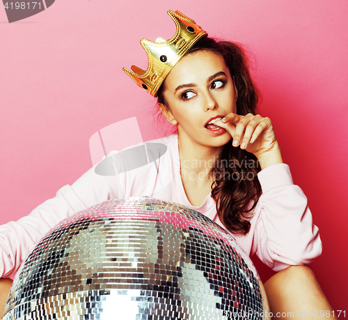 Image of young cute disco girl on pink background with disco ball and cro