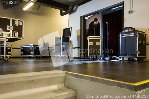 Image of Roadie leaning on a flightcase next to the stage