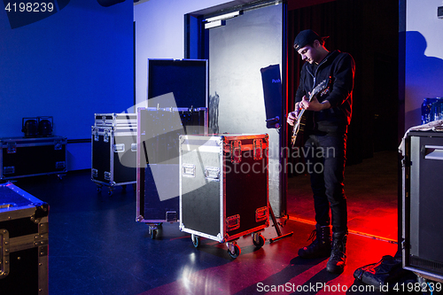 Image of Roadie playing guitar backstage