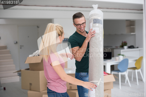 Image of couple carrying a carpet moving in to new home